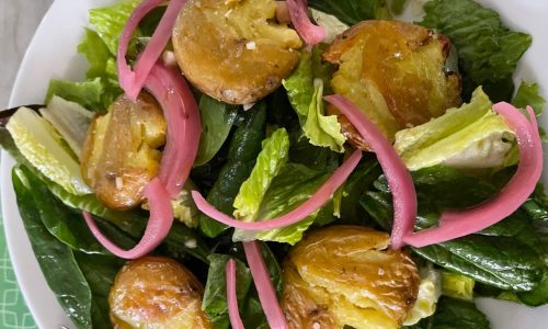 Recipe: This green salad is garnished with smashed potatoes warm from the oven