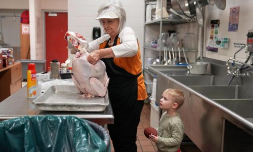 A cafeteria worker prepares a Thanksgiving meal to feed hundreds